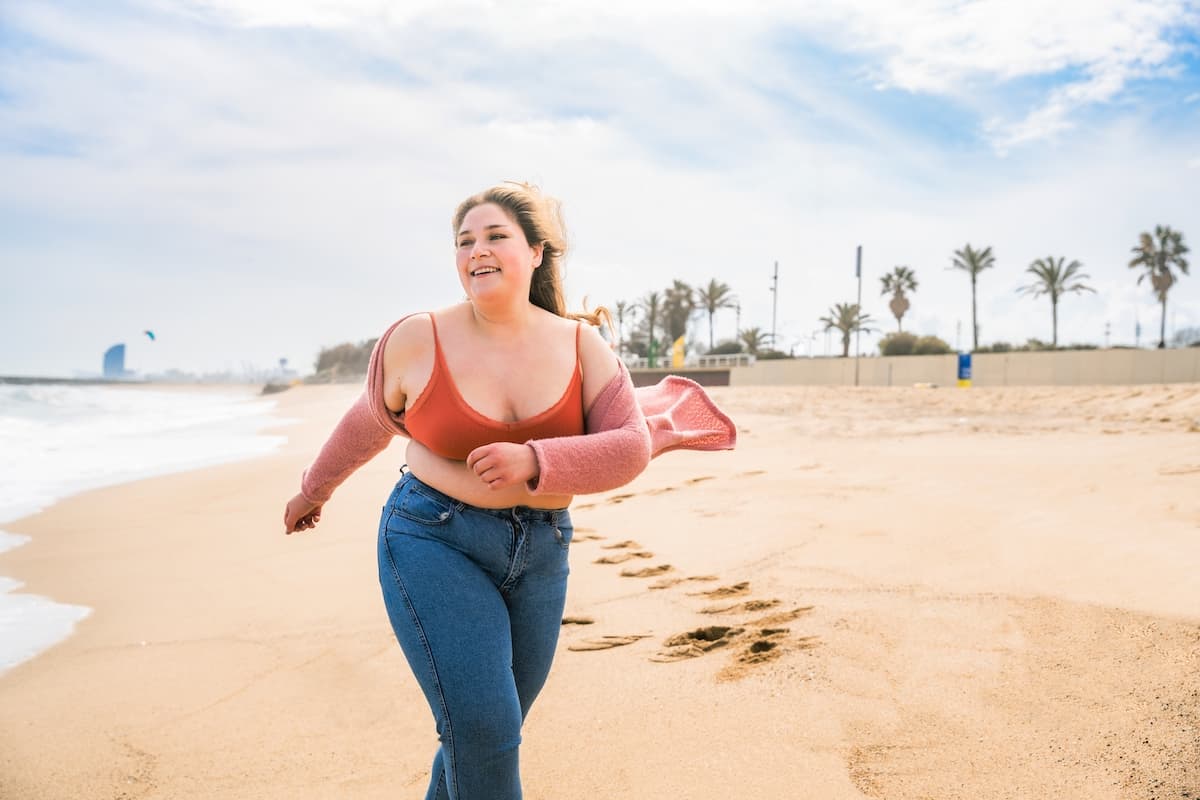 confident woman happily walking on the beach